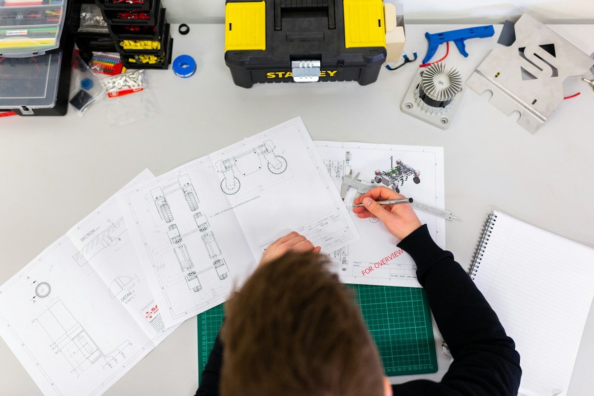 Engineering drawings and components being reviewed at a workstation